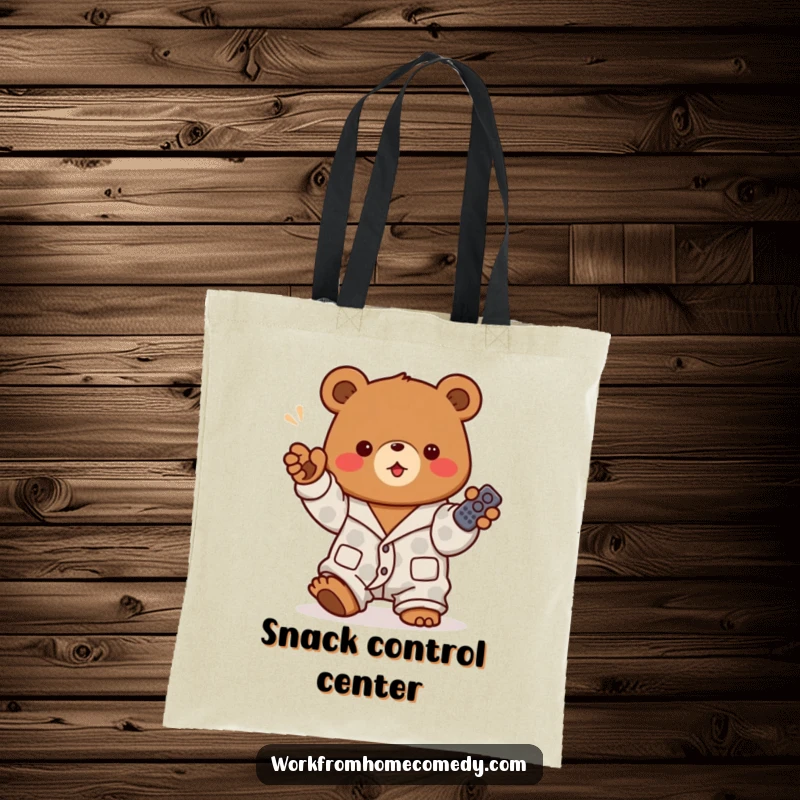 Funny brown bear in pajamas holding a remote control on a tote bag, ready to carry your relaxation essentials with authority.